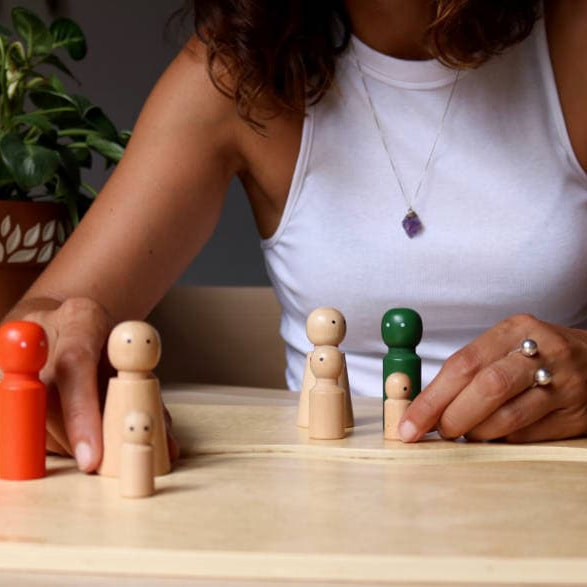 las manos de Carol agrupando unas figuras de madera