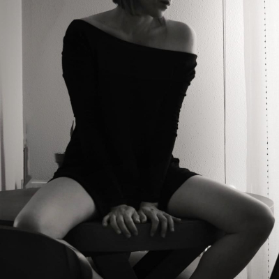 mujer sentada en un sofa, apoyada en él con las manos